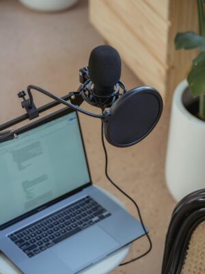 A modern podcast setup featuring a laptop and studio microphone on a desk, ideal for digital media production.
